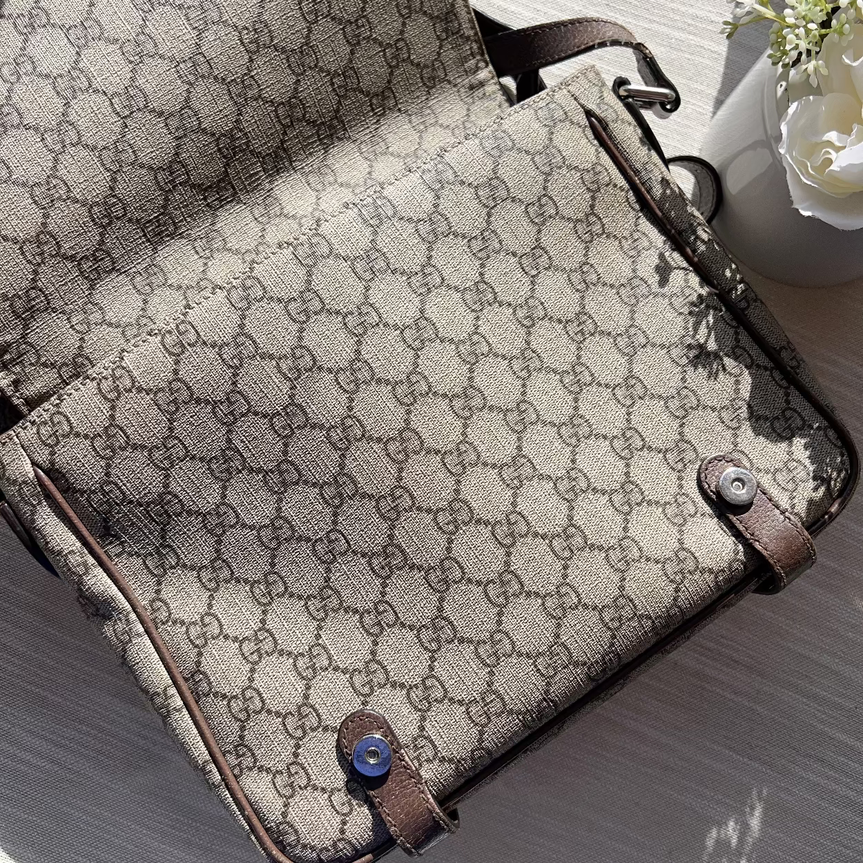 Designer handbag with patterned fabric and brown leather accents on a light surface.