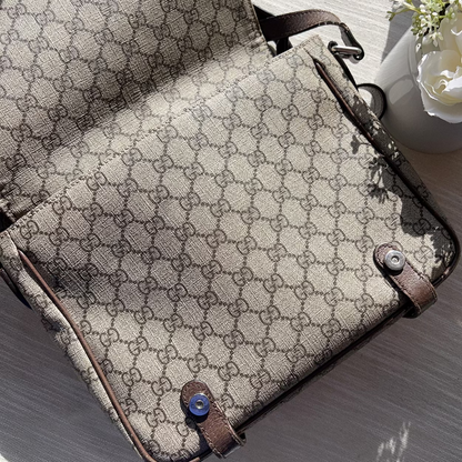 Designer handbag with patterned fabric and brown leather accents on a light surface.