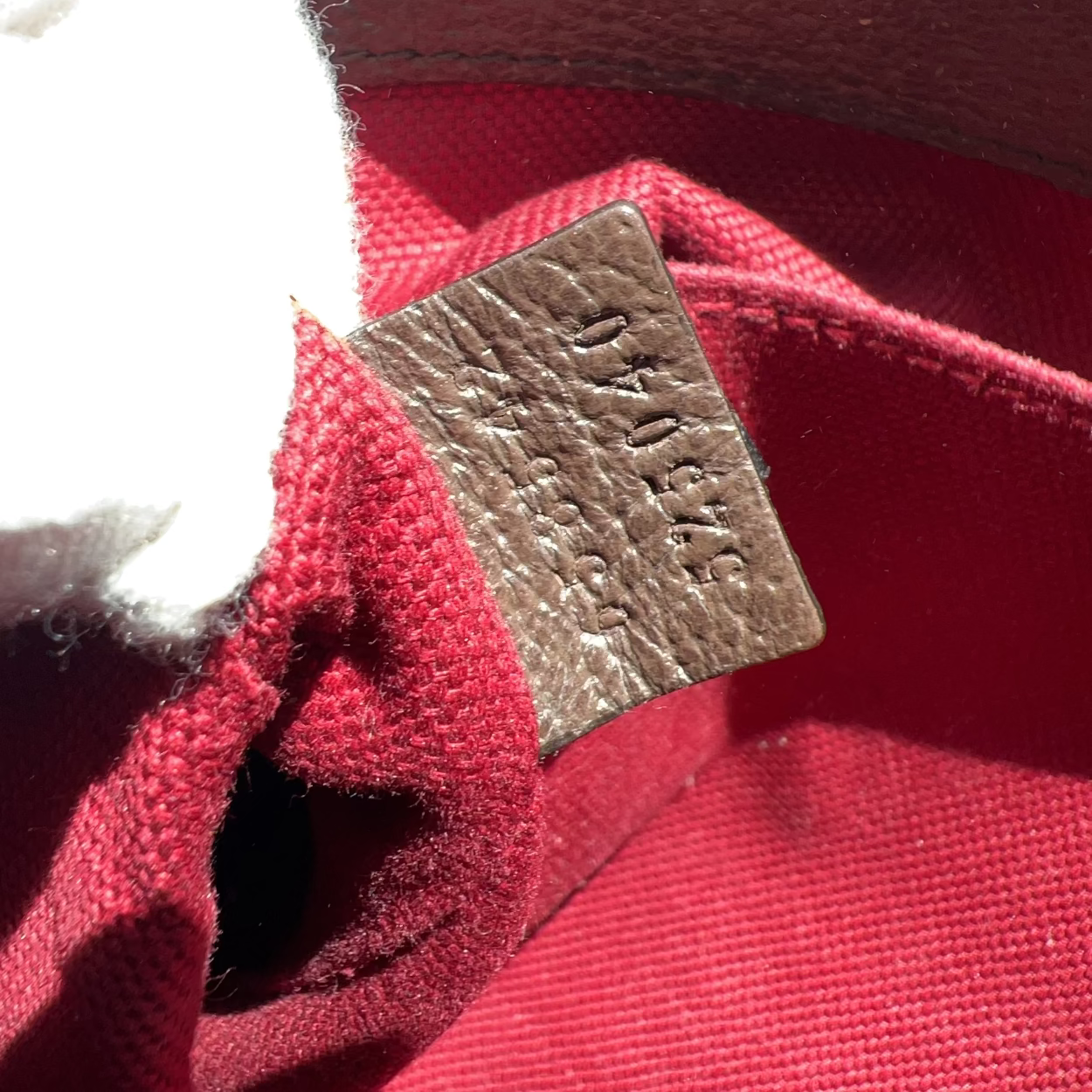 Close-up of a red fabric item with a brown tag featuring 'Bally' branding.