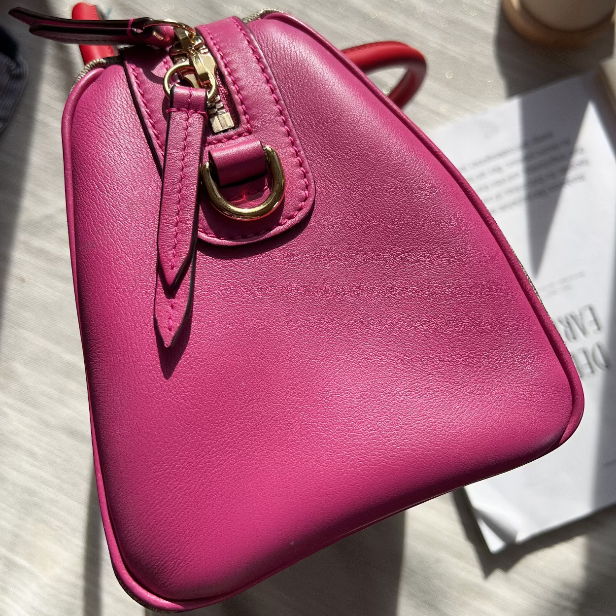 Pink handbag with gold clasp on a textured surface