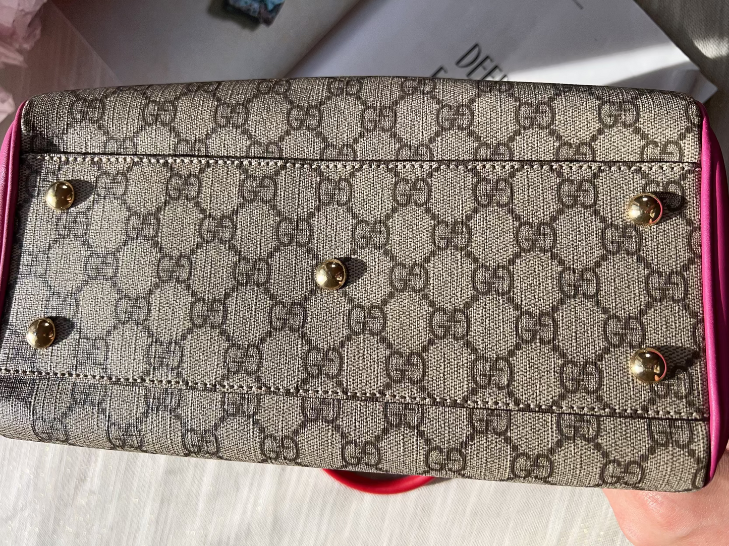 Patterned wallet with pink border held by a hand on a light background