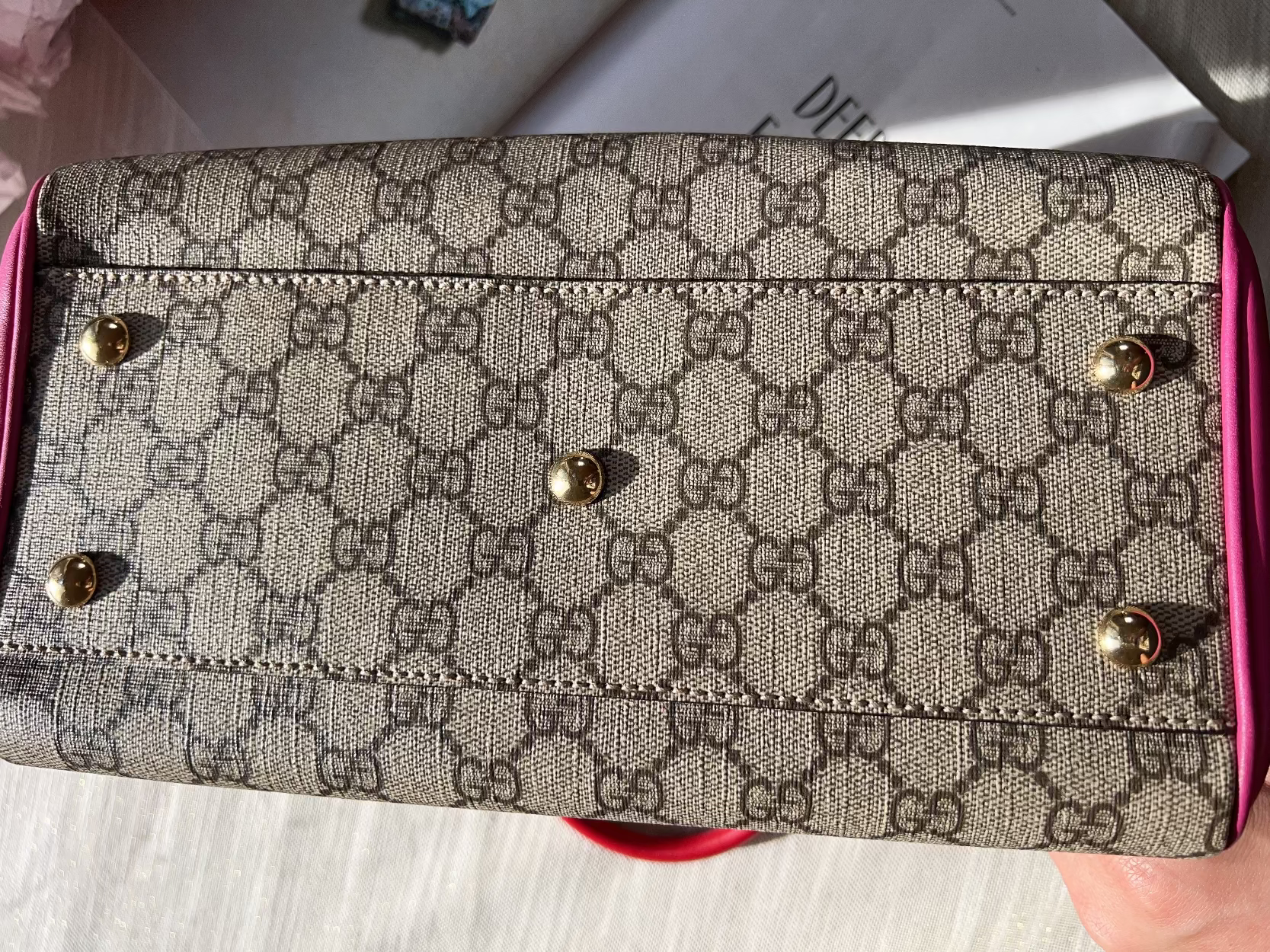 Patterned wallet with pink border held by a hand on a light background