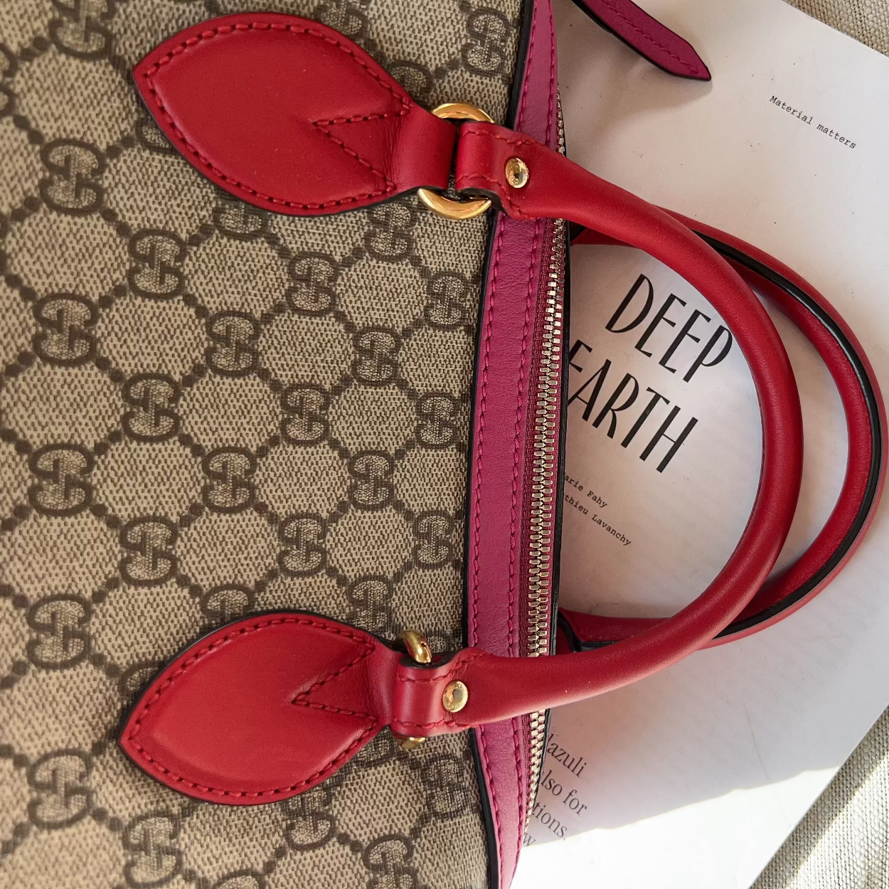 Red handbag with gold hardware on a patterned surface