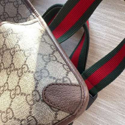 Designer handbag with patterned fabric and colorful strap on a textured surface