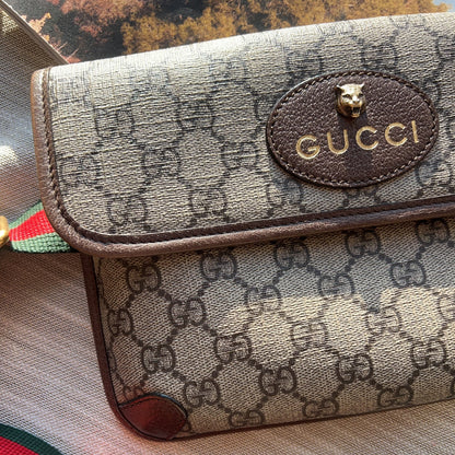 Gucci handbag with monogram pattern and visible logo on a striped background