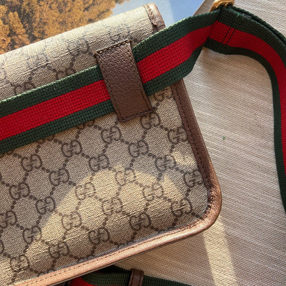Gucci handbag with iconic monogram pattern and red and green stripe on a textured surface.