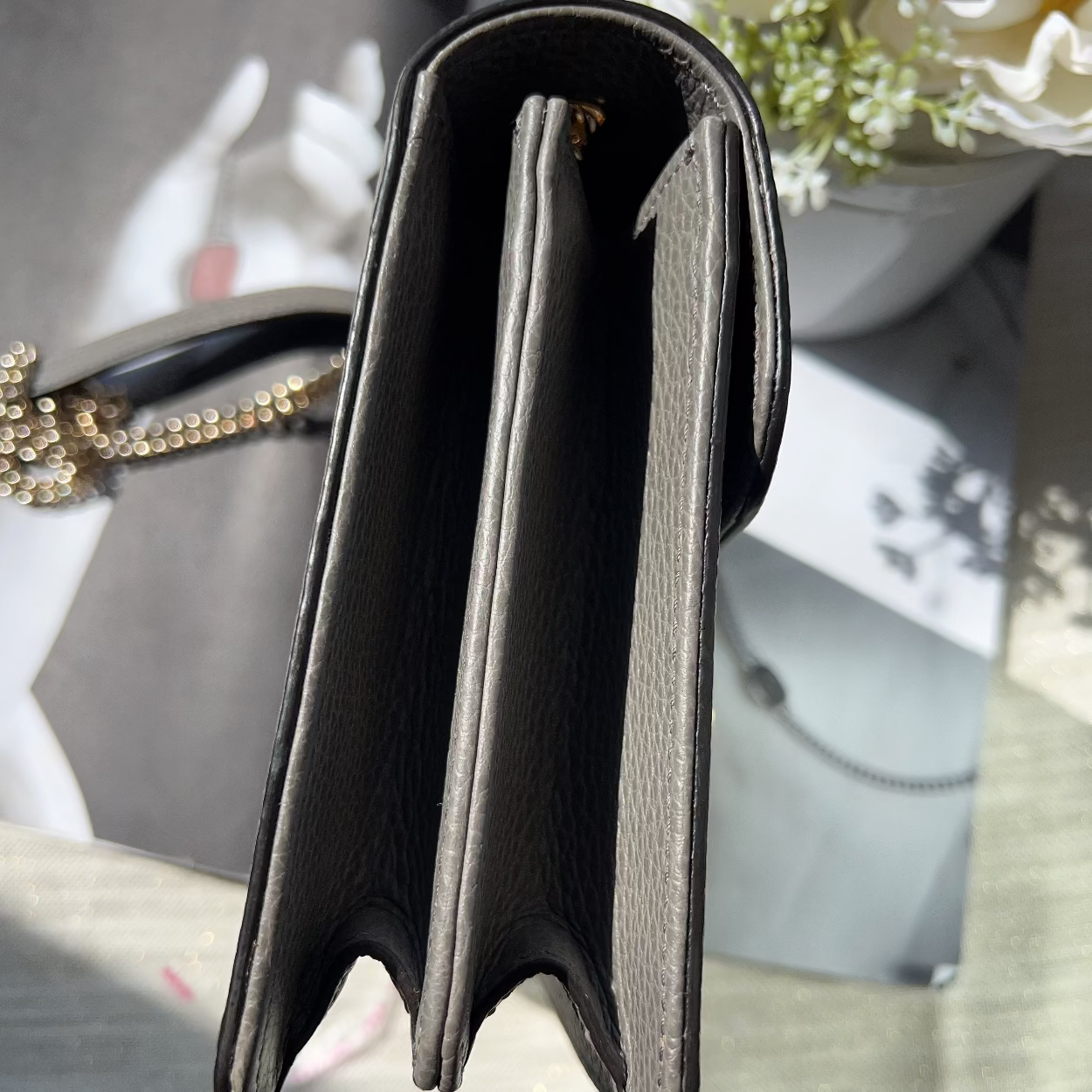 Black handbag with gold chain on a reflective surface