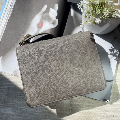 Gray textured clutch on a surface with a book and flowers in the background