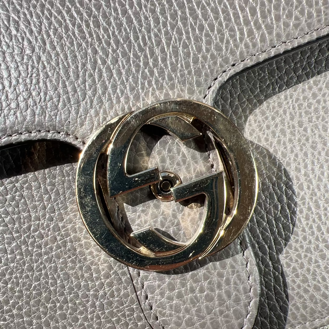 Close-up of a Gucci logo on a gray leather handbag