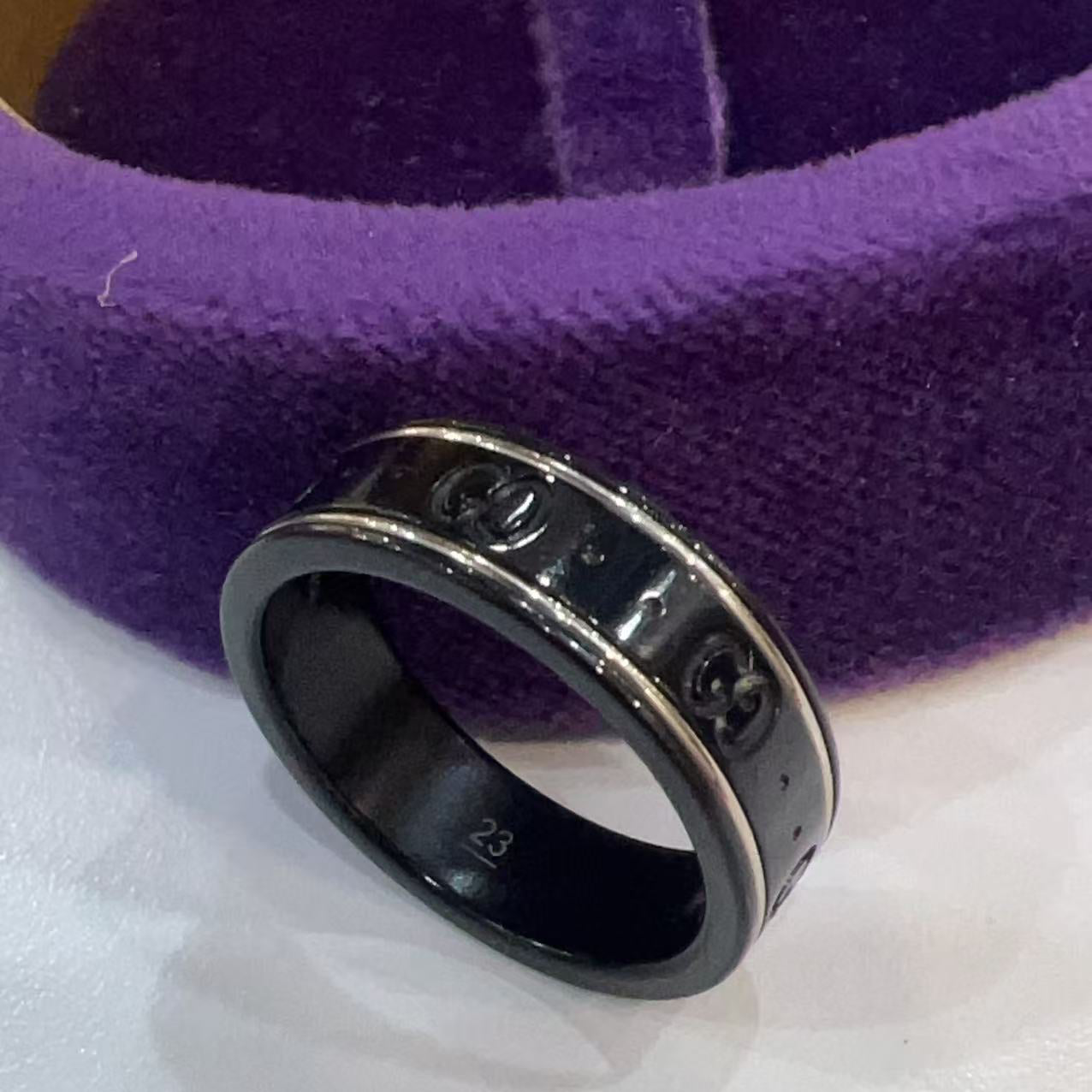 Silver ring with engraved text on a purple cushion