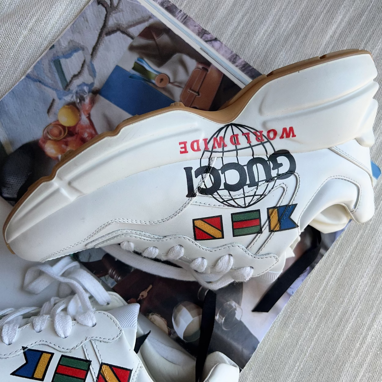 White sneaker with colorful flags and 'Gucci' logo on a blurred background