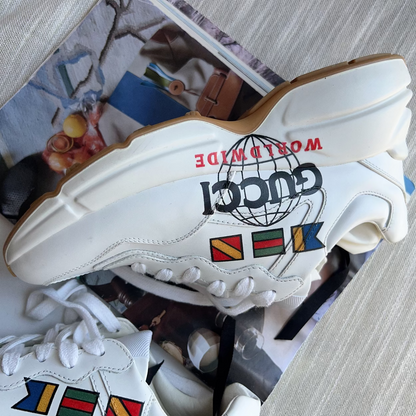 White sneaker with colorful flags and 'Gucci' logo on a blurred background
