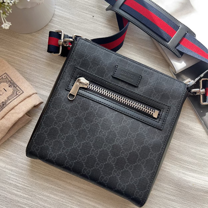 Black patterned crossbody bag with a visible brand logo on a light wooden surface.