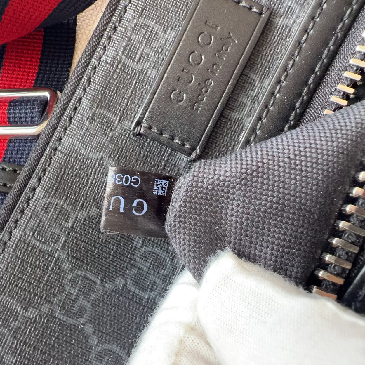 Close-up of a Gucci bag with red and blue strap and visible brand logo.
