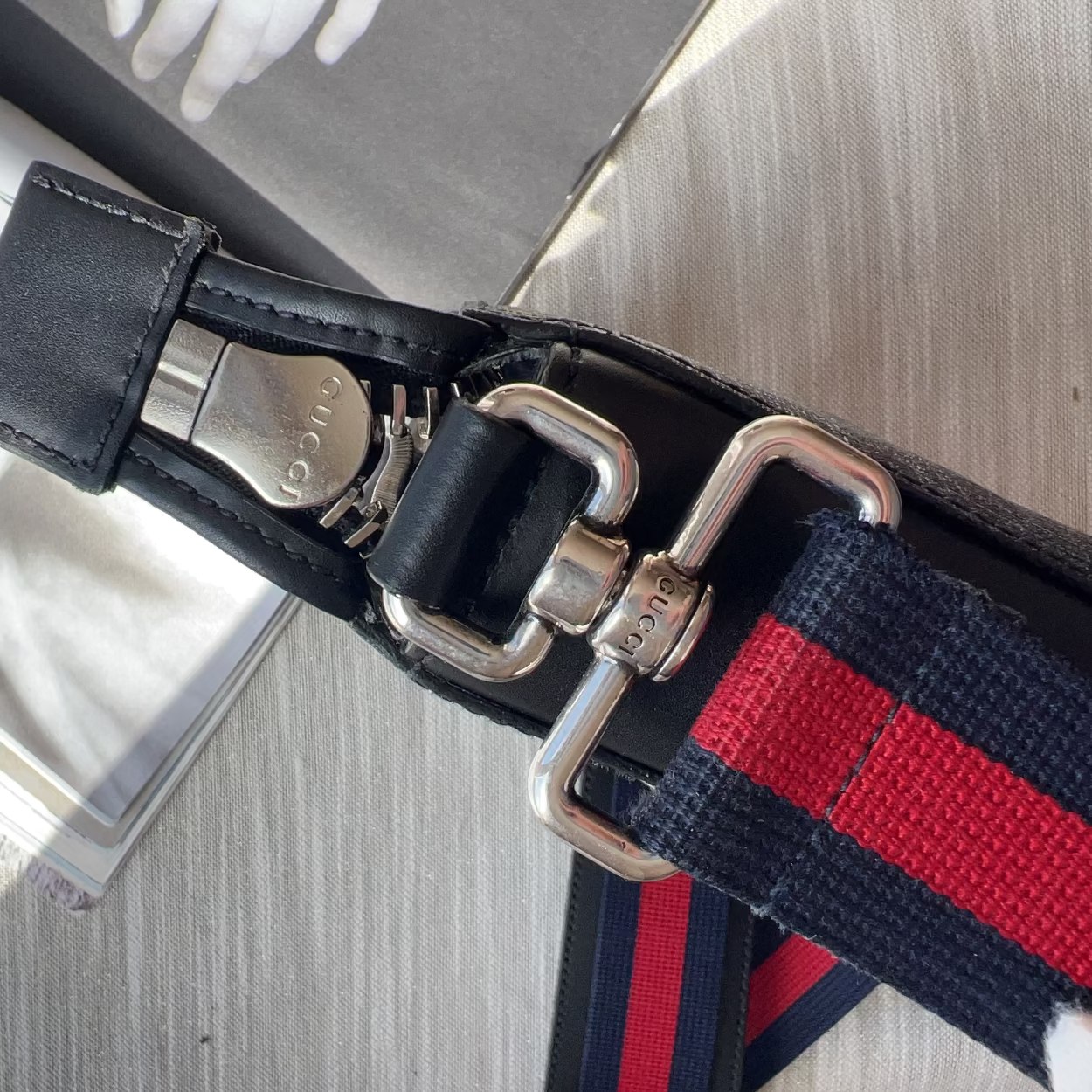 Close-up of a black strap with silver buckle on a textured surface