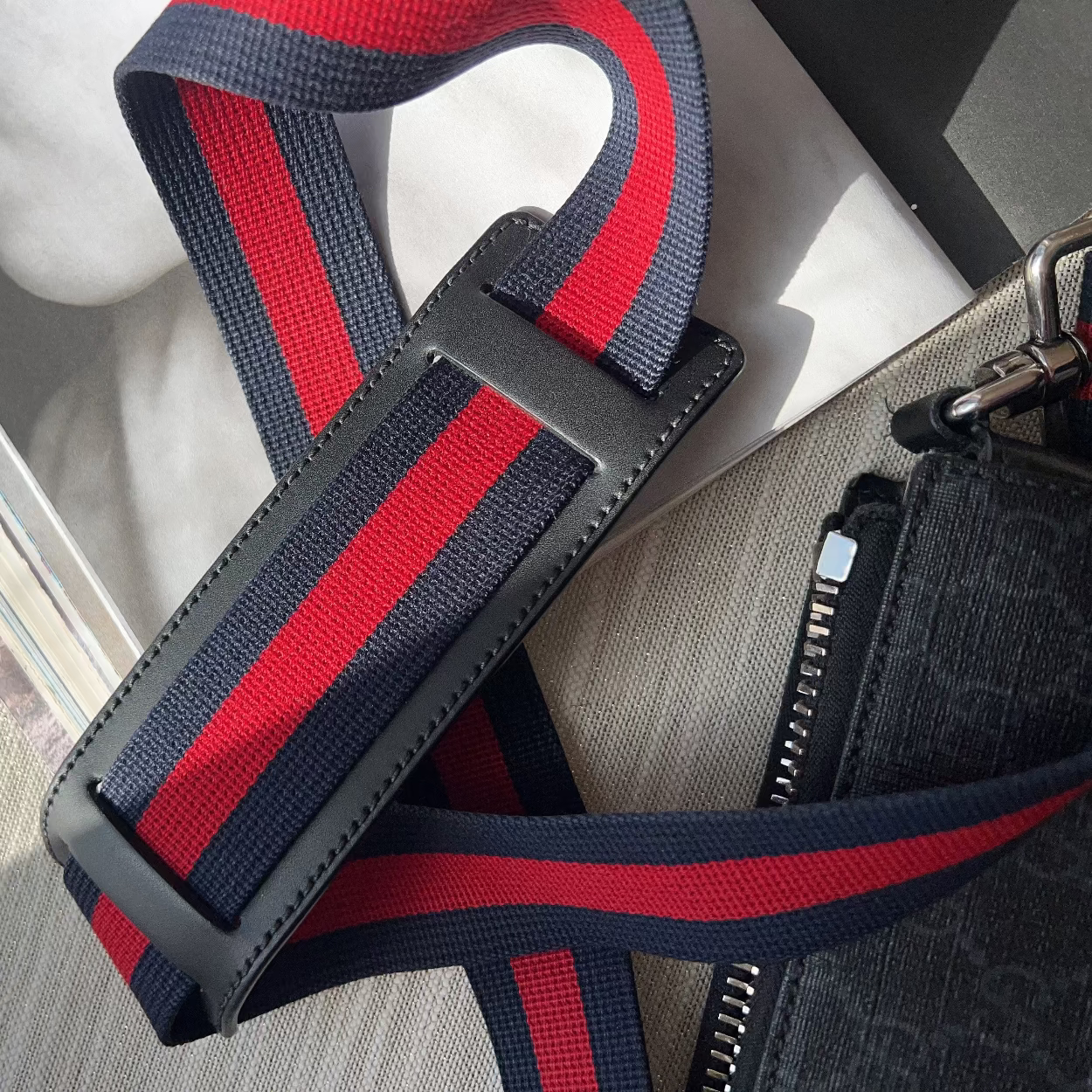 Red and black striped strap on a textured surface with a blurred background
