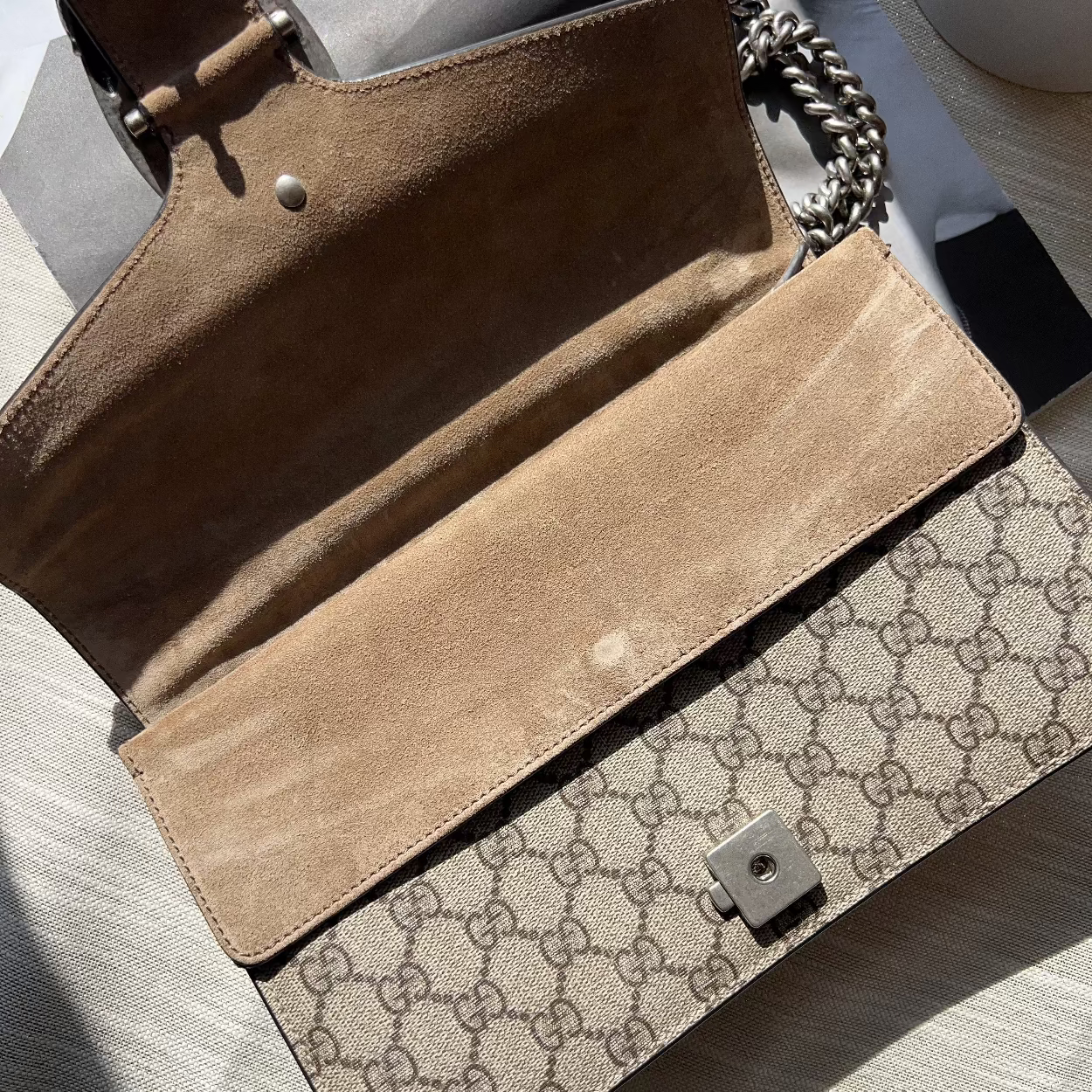 Open brown handbag with Gucci logo on a light surface