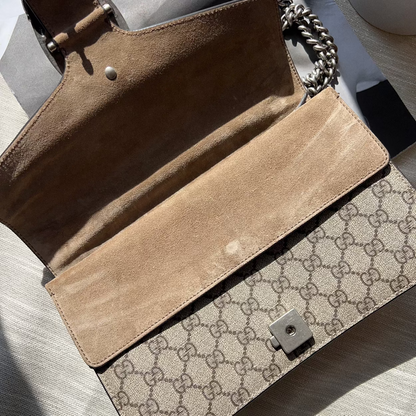 Open brown handbag with Gucci logo on a light surface