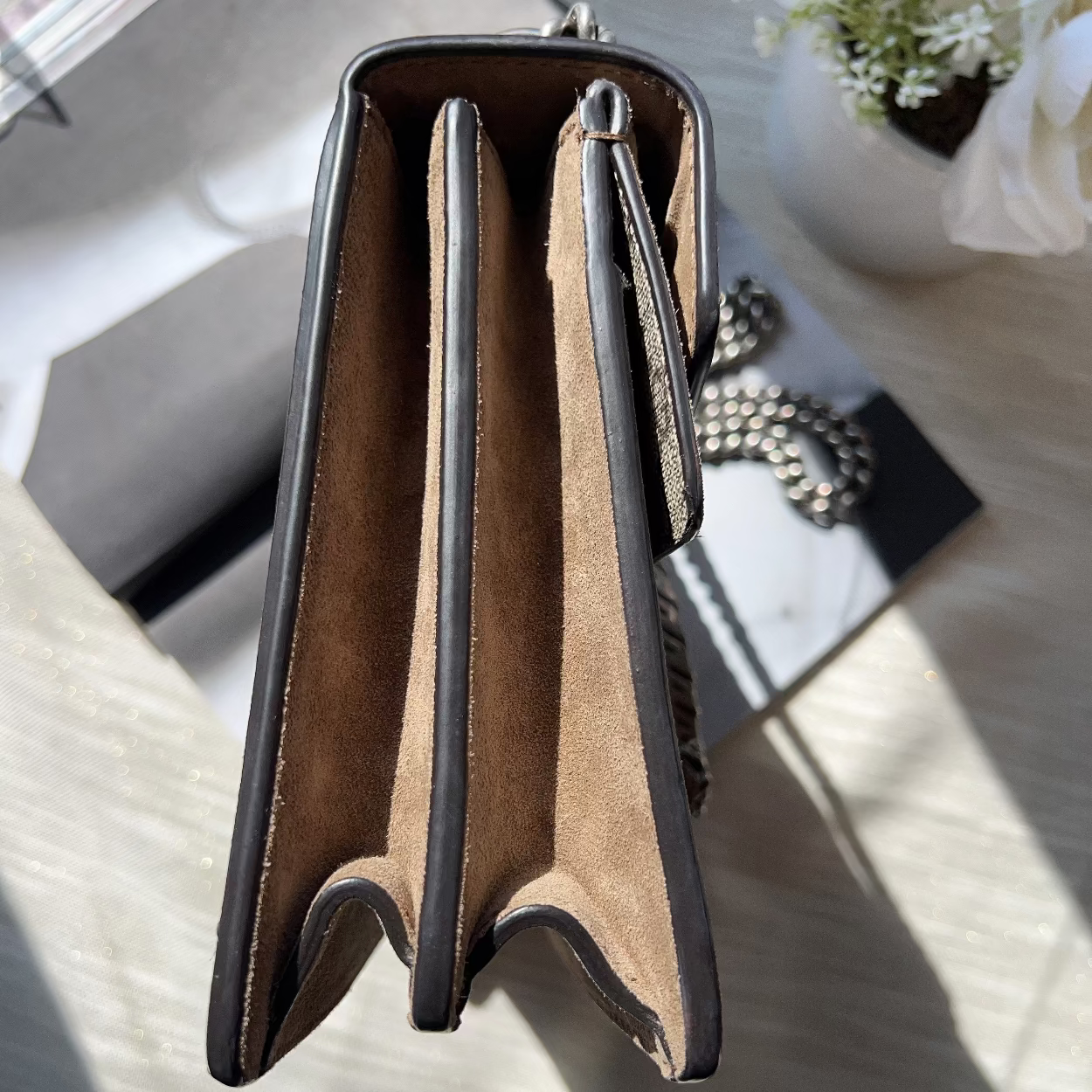Open brown leather wallet with black trim on a light gray surface.