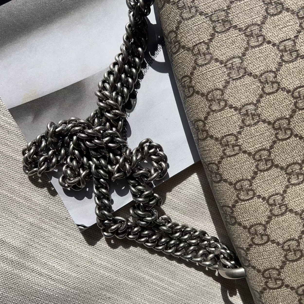Designer handbag with chain detail on a textured surface