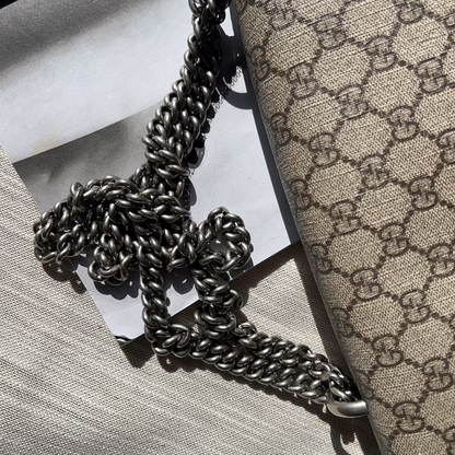 Designer handbag with chain detail on a textured surface