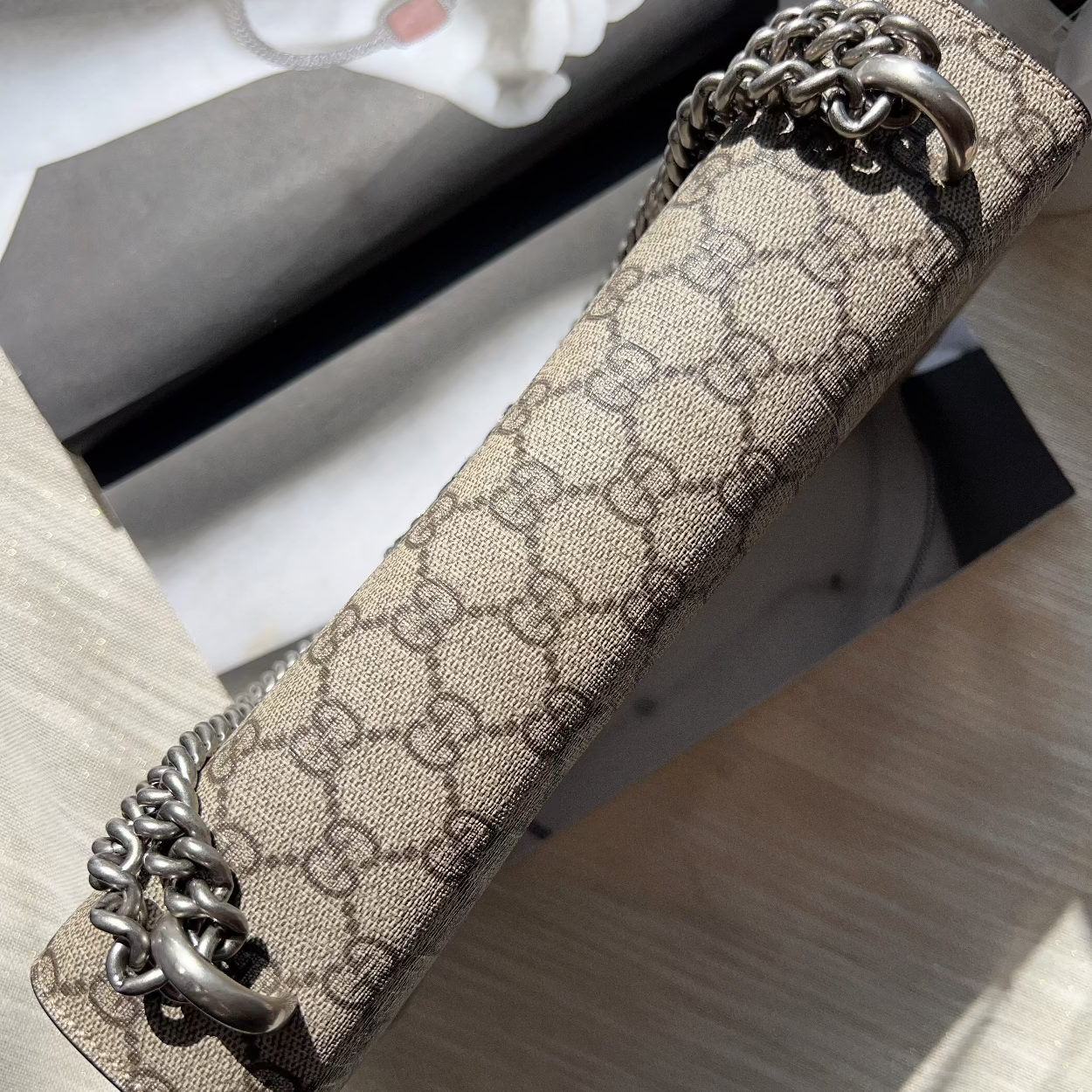 Designer handbag with chain detail on a textured surface