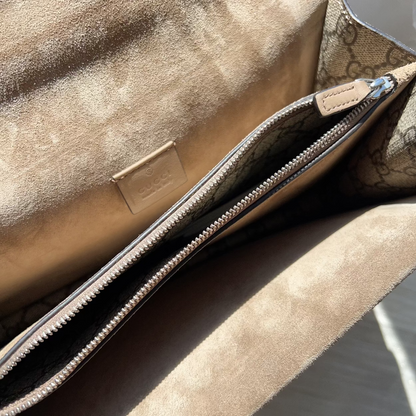 Close-up of a beige textured bag with a zipper, brand logo visible.