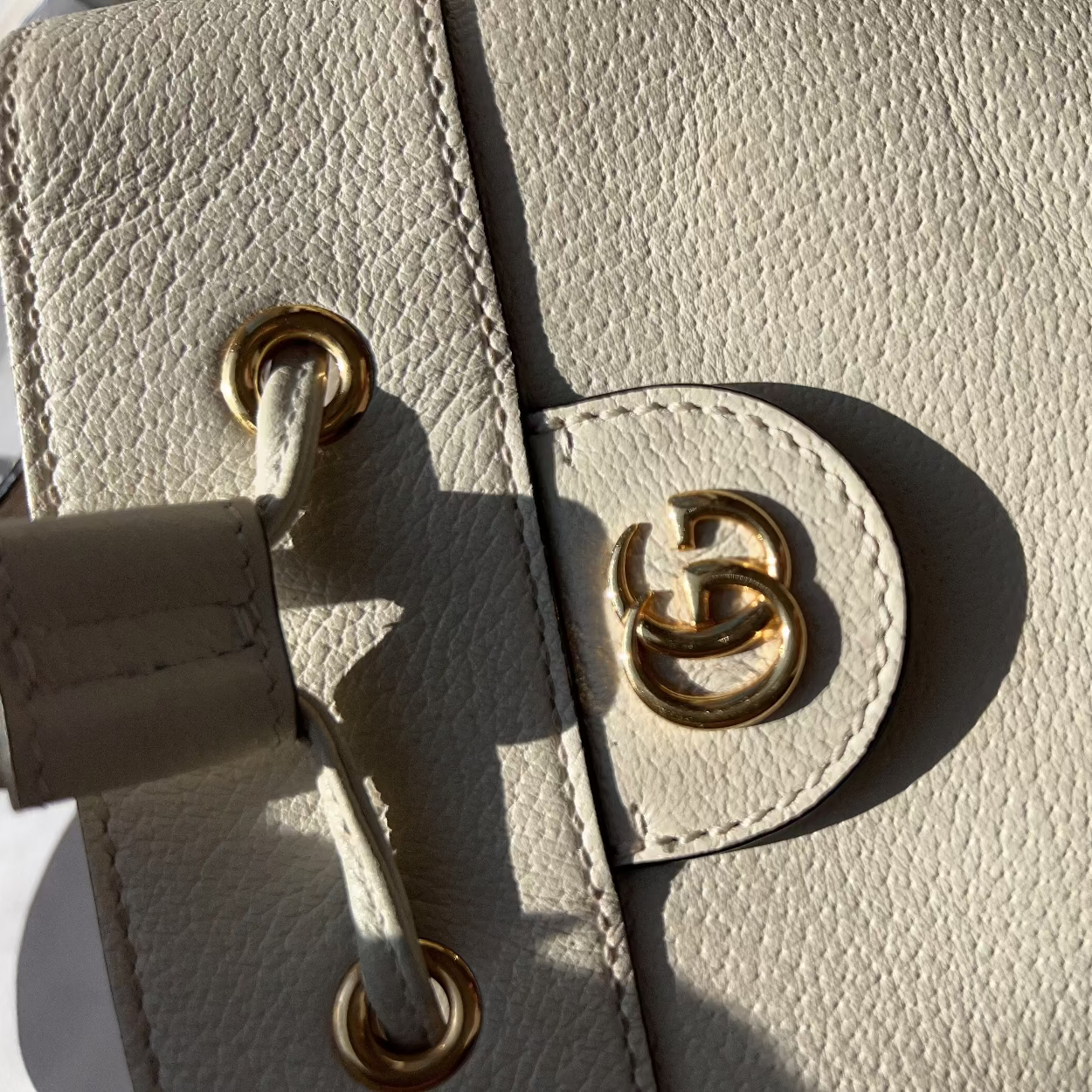 Close-up of a beige leather handbag with gold hardware