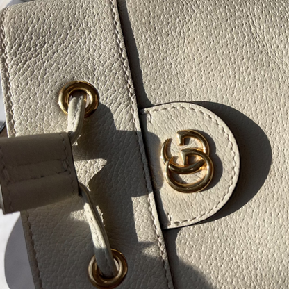 Close-up of a beige leather handbag with gold hardware