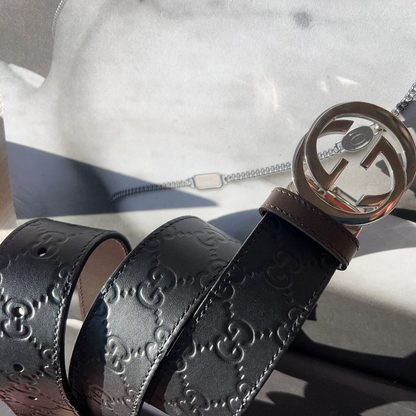 Black Gucci belt with a silver buckle on a marble surface