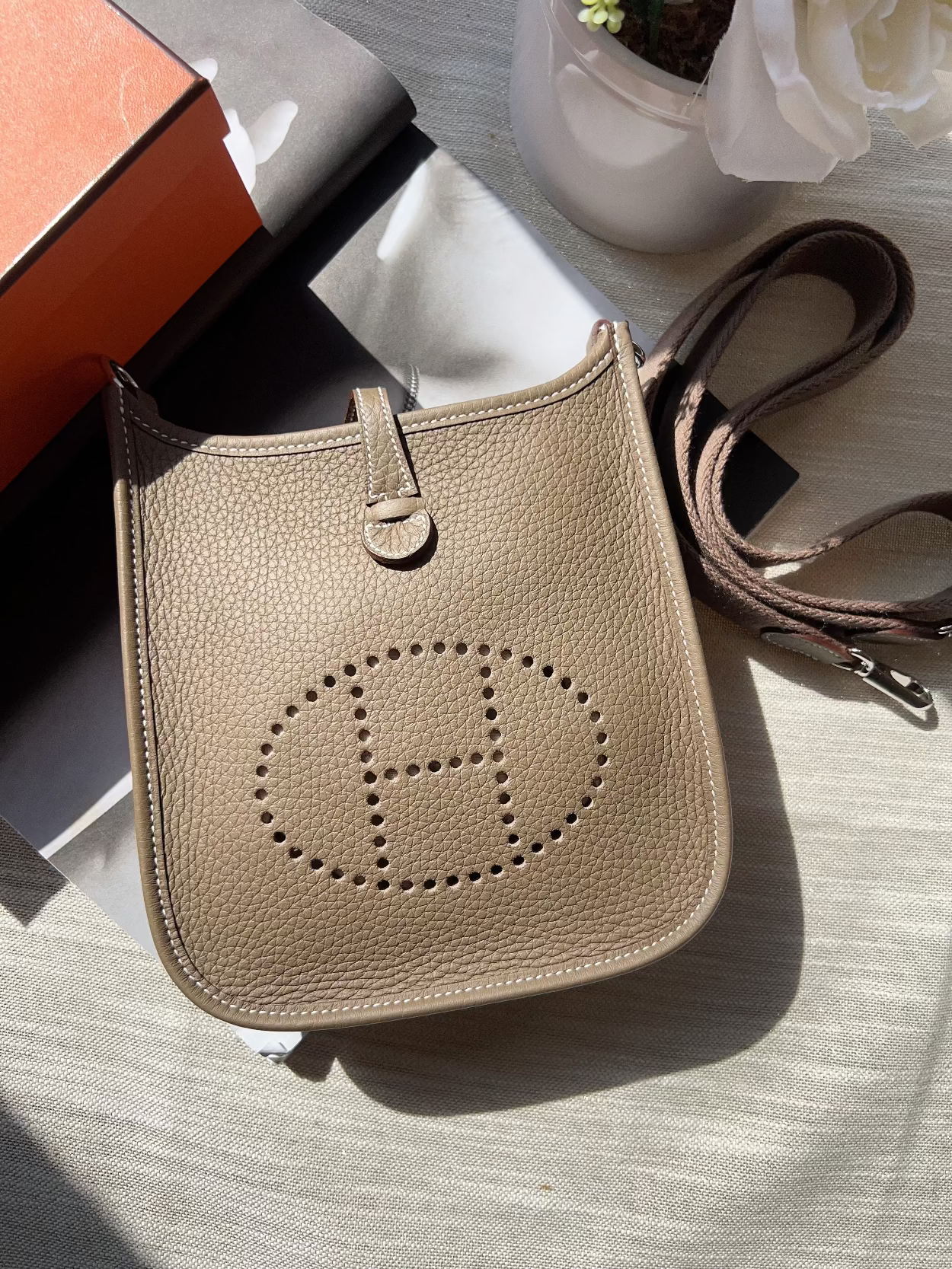 Beige handbag with brand logo on a light surface