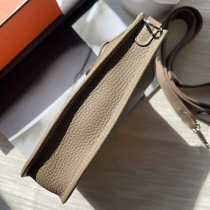 Brown textured handbag with a strap on a light surface