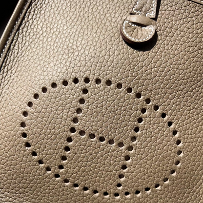 Close-up of a beige leather handbag with a circular cutout design.