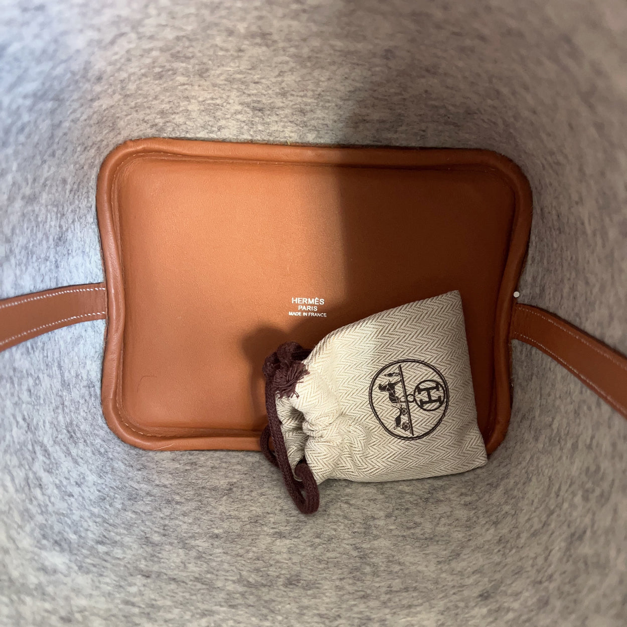 Brown leather pouch with a drawstring bag on a gray surface