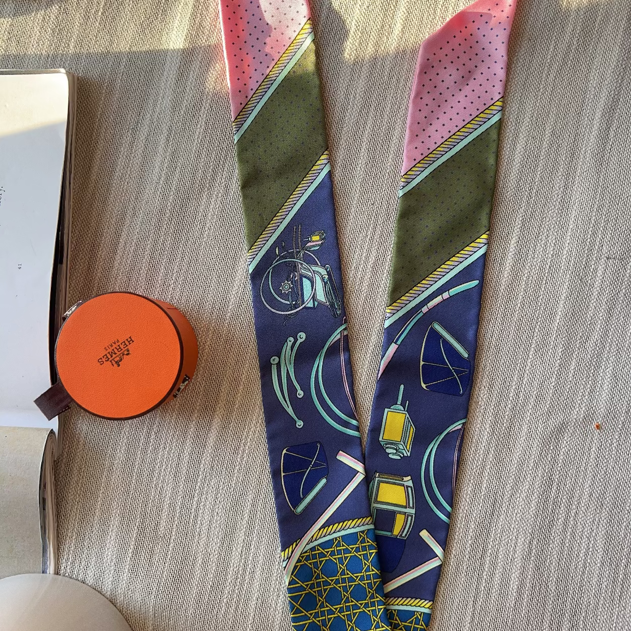 Colorful patterned tie on a wooden surface with an orange circular object.