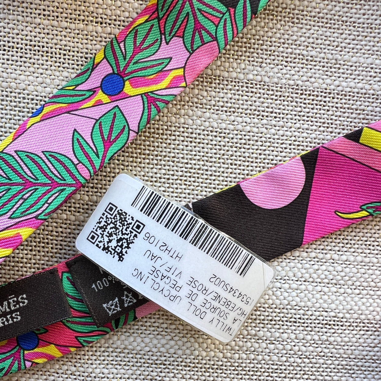 Colorful strap with a label and QR code on a textured fabric background