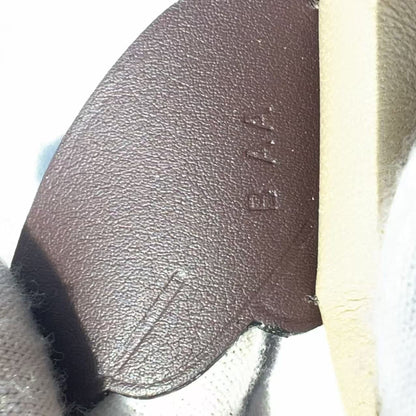 Close-up of a brown textured leather insole or footbed with embossed lettering, next to a cream-colored layer and a white knit fabric.