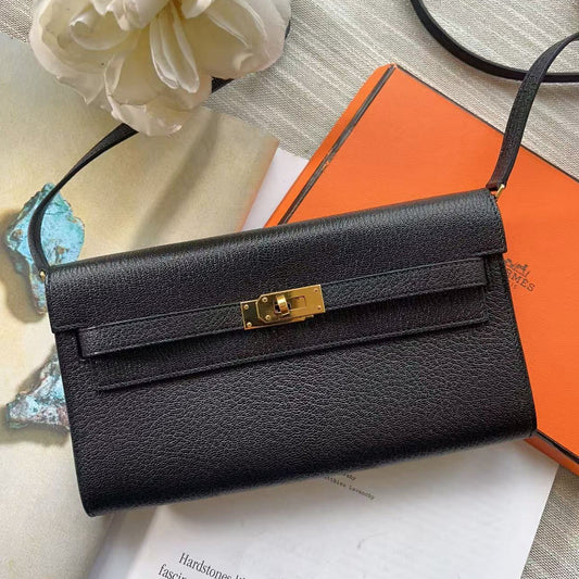 Black handbag with gold clasp on an orange box background