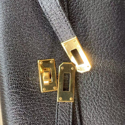 Close-up of a black leather bag with gold hardware on a dark background