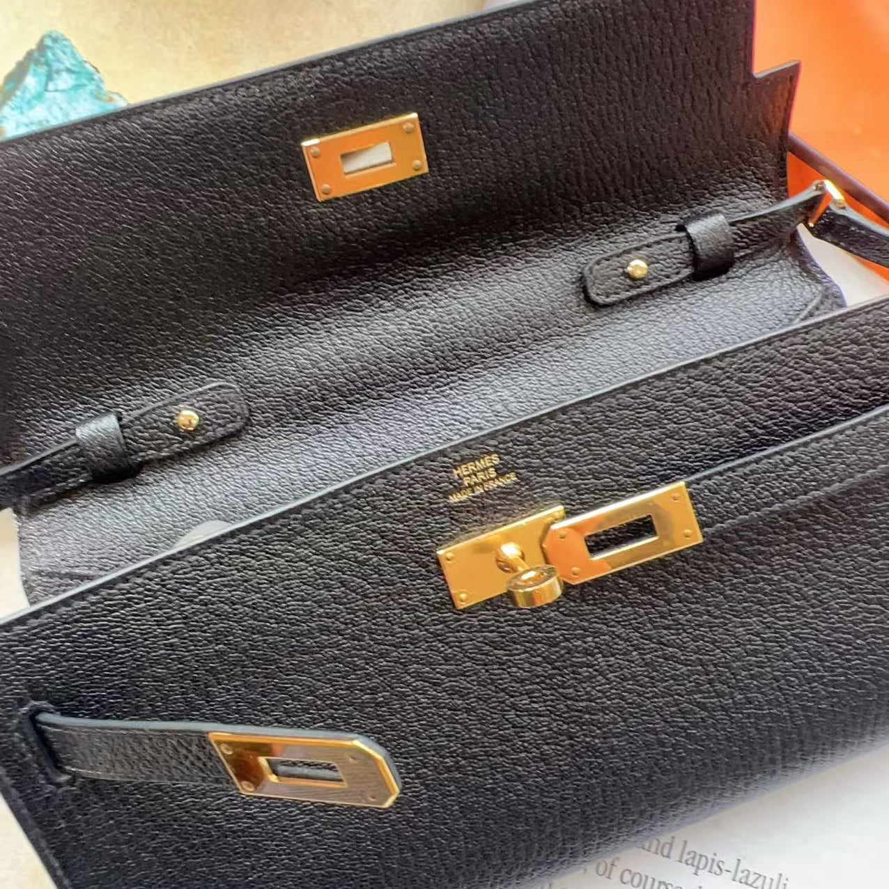 Black handbag with gold hardware on a textured surface