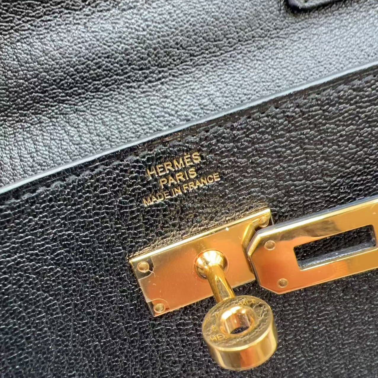 Close-up of a black leather Hermes bag with gold hardware.