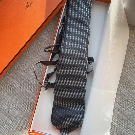Black patterned tie in an open orange box on a textured surface