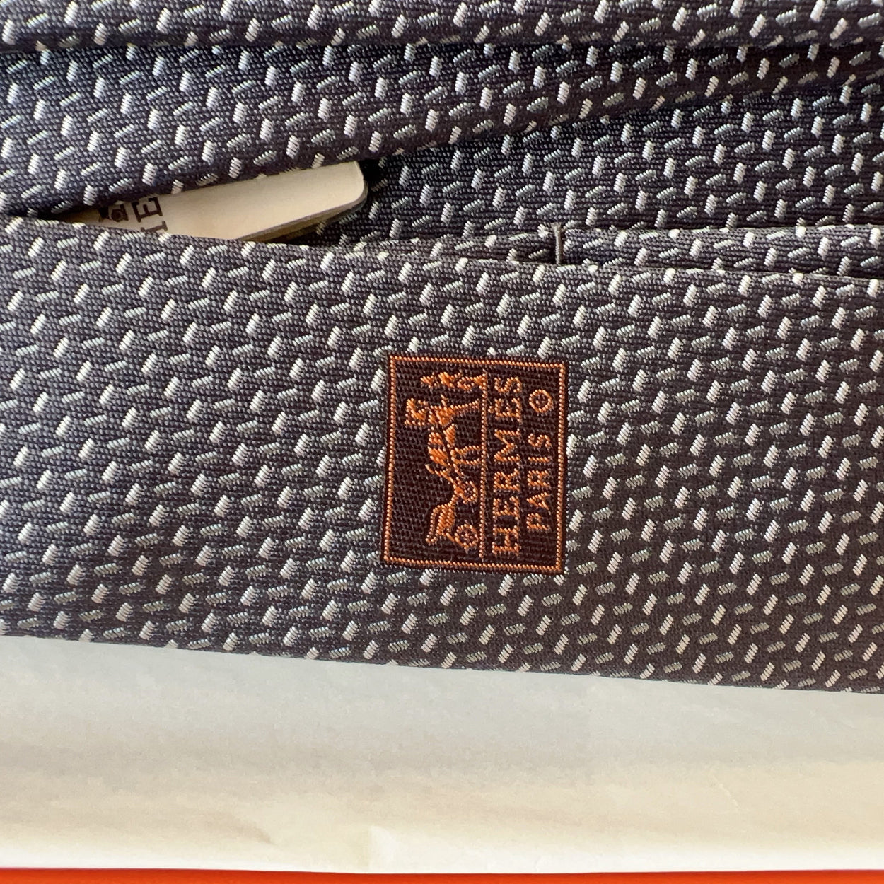Close-up of a woven fabric with a Hermès label on a product.