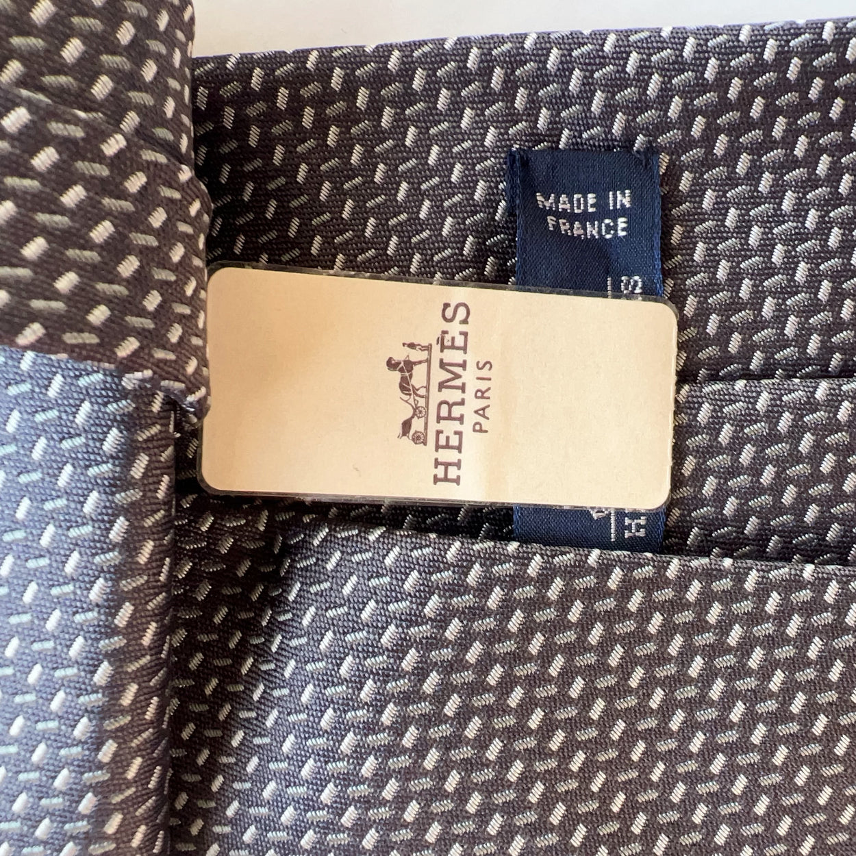 Close-up of Hermès fabric with a visible label on a textured background