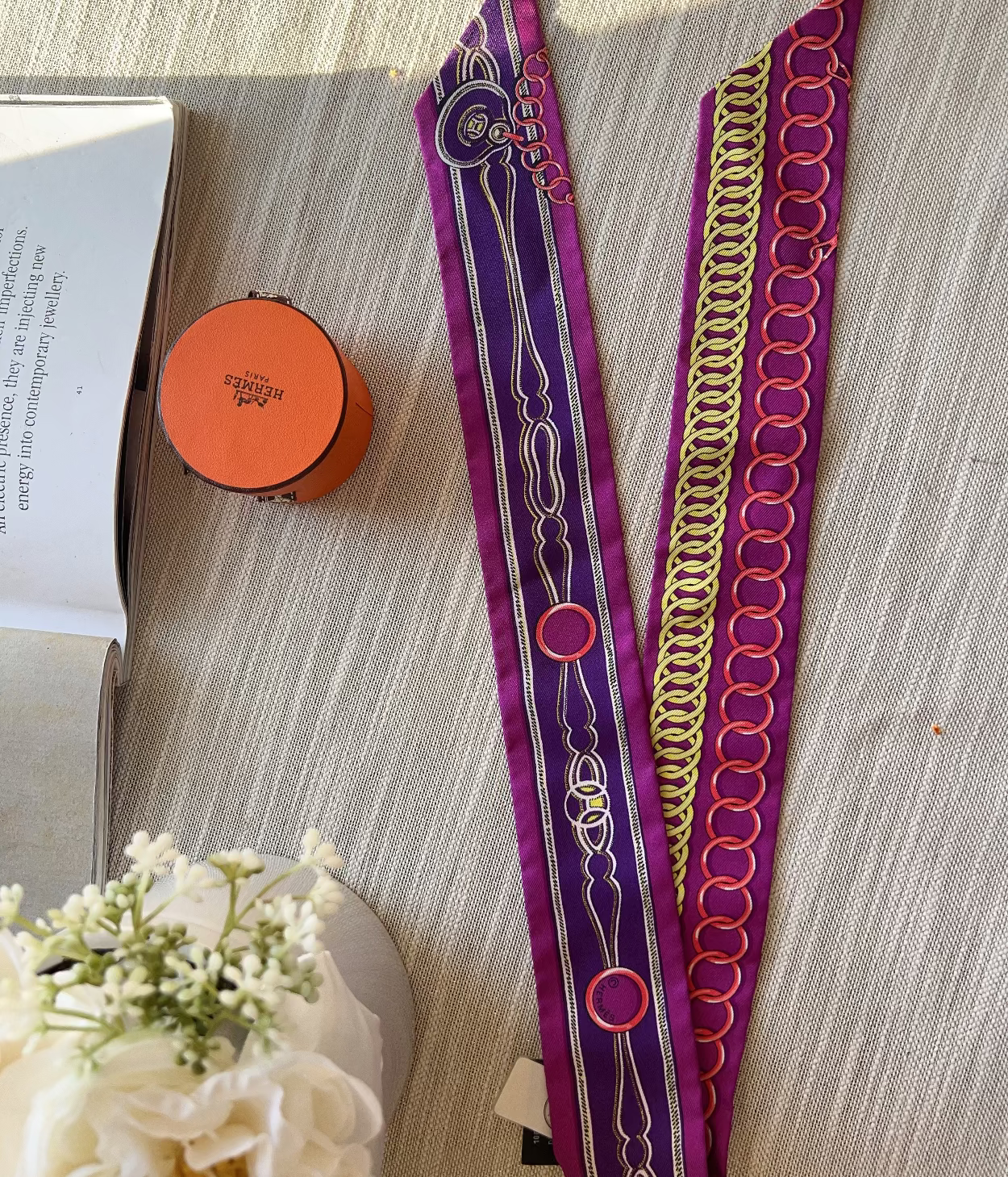 Decorative purple and gold headband on a textured surface with a book and flowers.