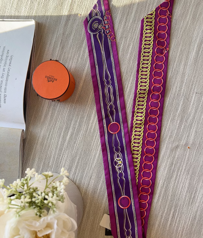 Decorative purple and gold headband on a textured surface with a book and flowers.