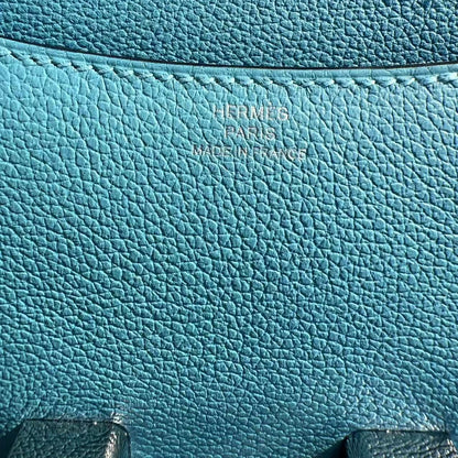 Close-up of a blue leather bag with 'Hermes' branding.