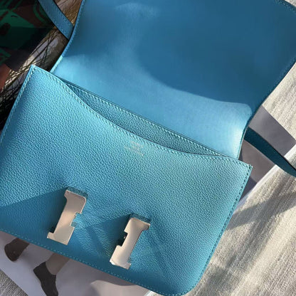 Blue handbag with silver clasp on a textured surface