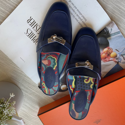 Pair of blue loafers with colorful interior on a magazine and orange box.