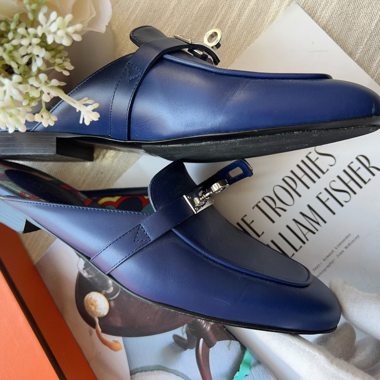 Blue loafers on a magazine with flowers in the background